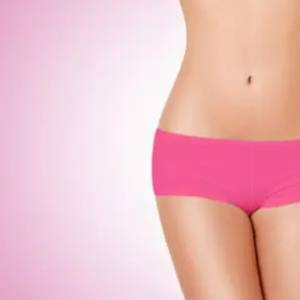 A woman in pink underwear standing next to a wall.